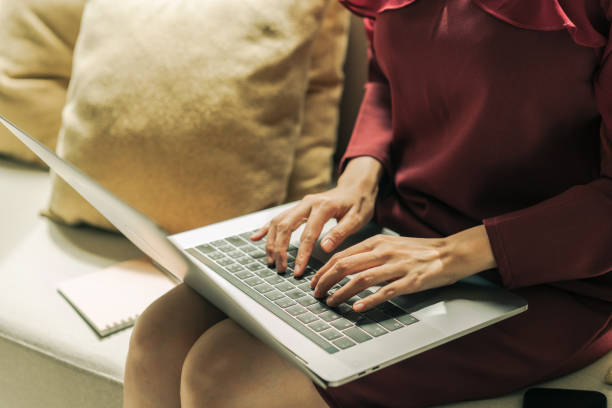 Asian Virtual assistant woman using laptop computer typing report to client.